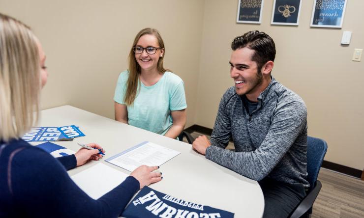 Two students meet with admissions counselor